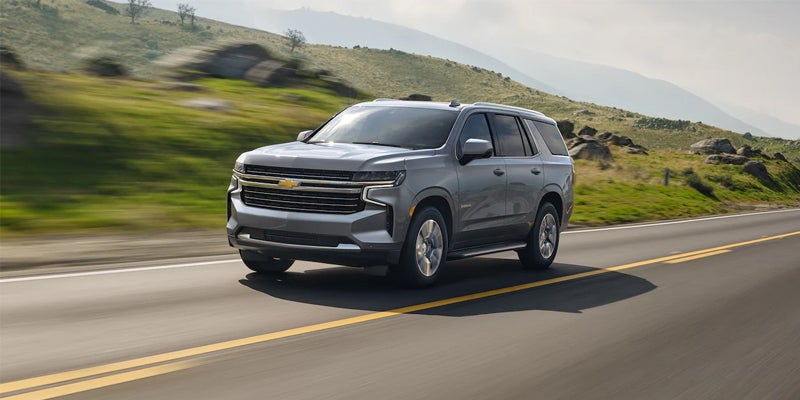 2022 Chevrolet Suburban driving on a road, showcasing its sleek design and powerful presence.