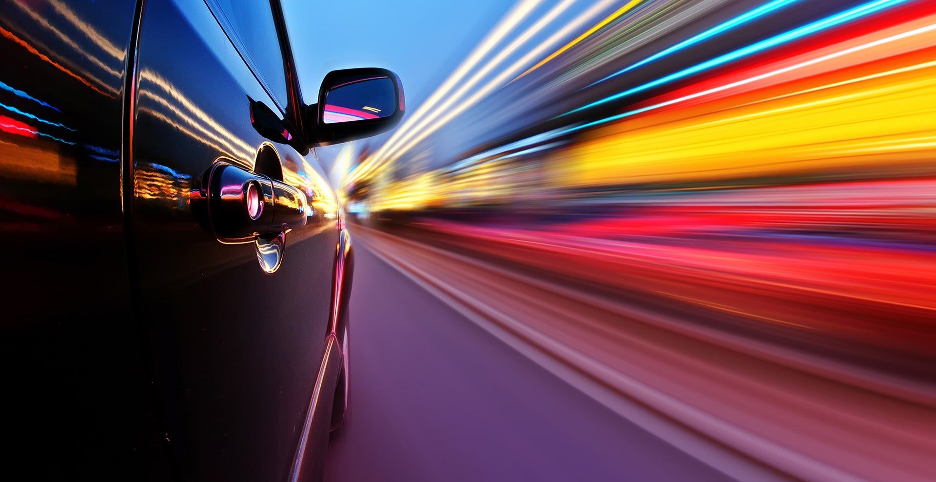 Car driving at high speed with colorful light trails.
